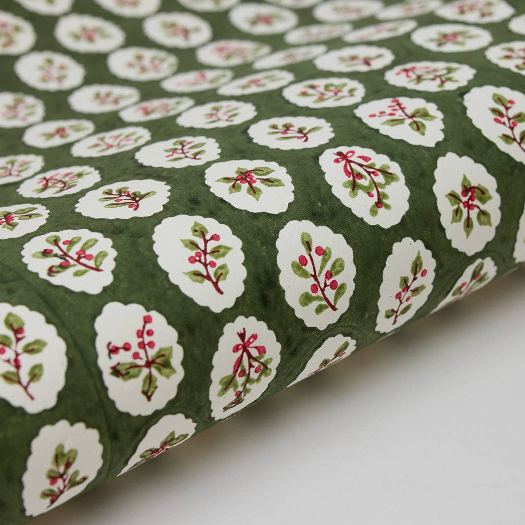 Roll of green fabric with white floral patterns on a white background